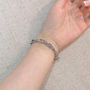 Detalle de una pulsera de cadena de plata S925 en la muñeca con eslabones vintage grabados