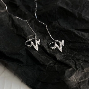 Macro view of S925 silver lightning bolt earrings with pavé zircons and long chain detail