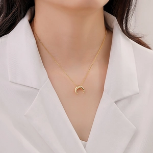 Collier minimaliste plaqué or avec pendentif demi-lune porté sur chemisier blanc