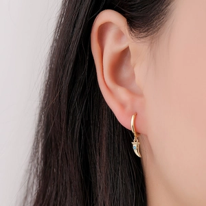 Elegant gold hoop earrings with turquoise crescent horn pendants on model with dark hair