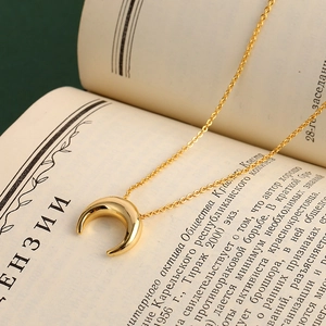 Collier élégant avec pendentif demi-lune dorée sur fond de page de livre vintage