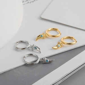 Macro view of S925 silver earrings with green zircon wolf tooth charms in gold and silver