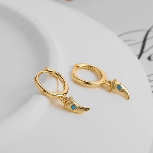 Macro detail of gold S925 silver earrings with green zircon and wolf tooth pendant