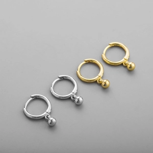 Macro detail showing silver and gold S925 sterling silver hoop earrings with bead pendants