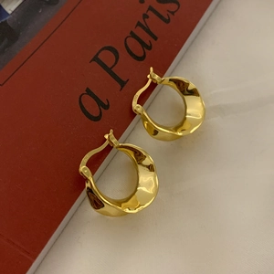 Detailed view of irregular wavy gold hoop earrings with S925 silver hallmark engraving
