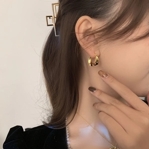 Close-up of elegant gold irregular textured hoop earrings worn by a female model