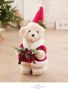 Detailed view of beige teddy bear with Christmas hat holding a plaid gift box decor