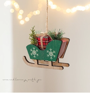 Detail of wooden Christmas sleigh with red plaid gift box and snowy pine needles