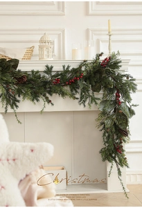 Üppige Weihnachtsgirlande mit Tannenzapfen und roten Beeren auf weißem Kaminsims