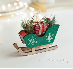 Detail of a mini wooden Christmas sleigh with snowflake patterns and red gift box