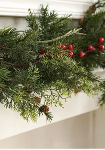 Detail der Weihnachtsgirlande mit Tannennadeln, roten Beeren und Zapfen am Kamin