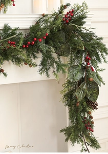 Weihnachtsgirlande mit roten Beeren und Tannenzapfen auf weißem Kaminsims im Detail