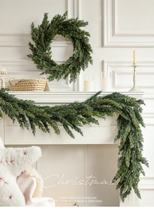 Close-up of realistic pine Christmas wreath and garland hung on a white fireplace mantle