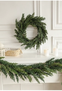 Close-up of artificial pine Christmas wreath and garland on a white fireplace mantel