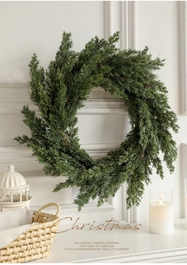 Close-up of realistic green pine Christmas wreath on a white wall with festive decorations