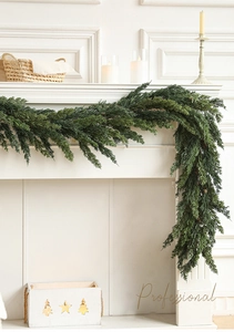 Detailed view of dense evergreen garland on a white fireplace with festive decor