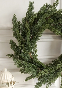 Close-up of realistic pine needle Christmas wreath on a minimalist white wall