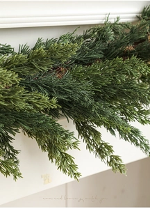 Close-up of artificial cedar Christmas wreath with realistic needles on white mantel