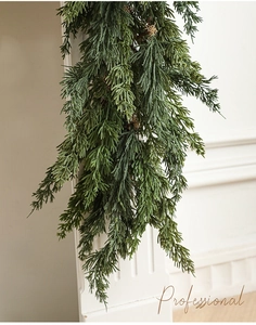 Close-up of frosted green cypress garland hanging on a white wall for Christmas decor