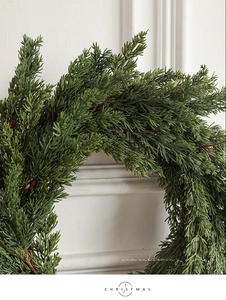 Close-up of artificial pine needle Christmas wreath with natural texture on white wall