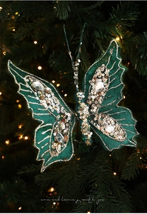 Detail of dark green butterfly ornament with gold sequins on a lit Christmas tree