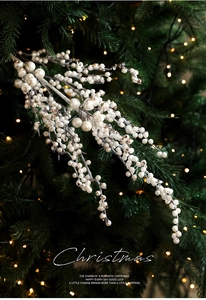 Detail of white glittery Christmas berry branch pick with festive tree lights background