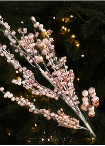 Close-up of champagne glitter berry stems against blurred warm Christmas lights background