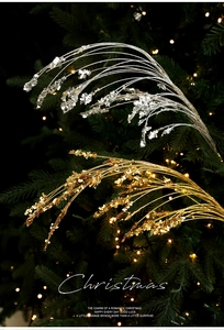 Close-up of glittery gold and silver Christmas glitter picks with festive tree background