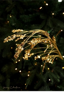 Close-up of sparkling gold glitter floral picks on a green Christmas tree with soft bokeh