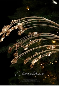 Close-up of champagne gold glitter stems and sequin branches on a green Christmas tree
