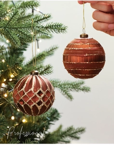Nahaufnahme von bronzenen Weihnachtskugeln mit goldenem Glitzer und Streifenmuster