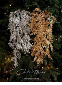 Détail de branches de cèdre de Noël dorées et argentées givrées sur un sapin illuminé