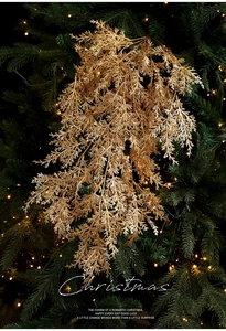 Détail d'une branche de pin dorée pailletée sur un sapin de Noël avec lumières chaudes