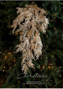 Vue détaillée d'une branche de cèdre pailletée dorée sur un sapin de Noël