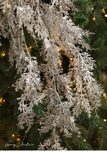 Gros plan d'une branche de pin argentée scintillante avec paillettes sur un sapin de Noël