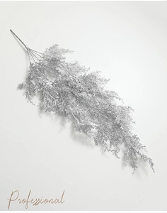 Gros plan d'une branche de cèdre artificielle argentée à paillettes avec texture fine