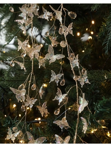 Close-up of iridescent crystal butterfly ornaments hanging on a festive Christmas tree branch