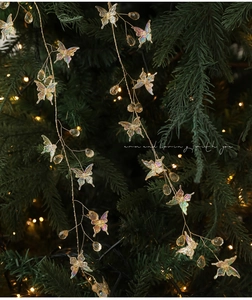 Iridescent butterfly and teardrop beads on a Christmas tree with warm bokeh lighting