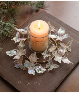 Close-up of iridescent butterfly ornaments on a festive candle ring with warm glow