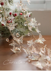 Close-up of iridescent crystal butterfly ornaments with pearl beads on a festive pine branch