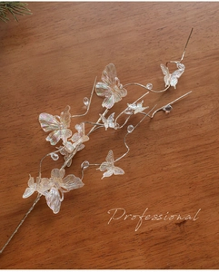 Close-up of iridescent butterfly ornaments on silver wire branch for Christmas decor