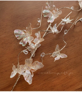 Macro detail of iridescent butterfly hair accessories with golden wire and clear beads