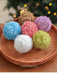 Detailed close-up of colorful woven Christmas ornaments in a rustic wicker tray