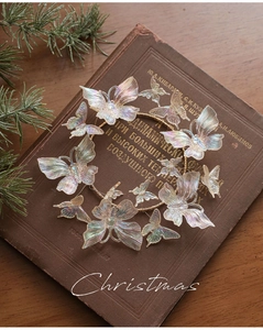 Close-up of colorful iridescent butterfly wreath with gold wire on a vintage book