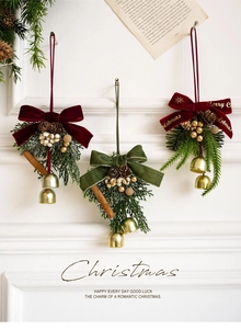 Detail of Christmas ornaments with velvet bows, pine cones and gold bells on a white wall