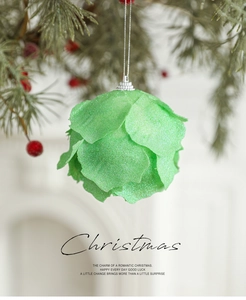 Close-up of green petal-shaped Christmas ball with glitter on a pine tree branch