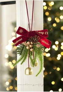 Detail of red velvet bow with golden pinecone and bells for Christmas tree decor