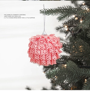Detail of pink lace Christmas ball with hollow weave hanging on tree with lights