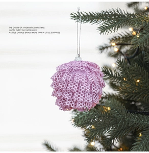 Detail of pink lace Christmas ball ornament with fine mesh hanging on a decorated tree
