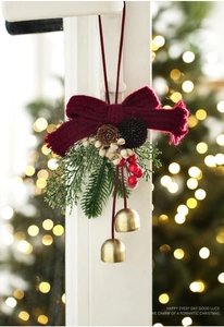 Close-up of velvet bow Christmas ornament with bell, pine cones and red berries decor